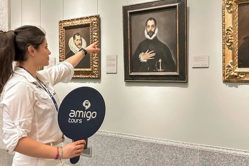 투어 가이드가 '아미고 투어' 라고 적힌 패들을 들고 박물관에 있는 그림을 가리킵니다. 근처에 또 다른 그림이 있습니다.