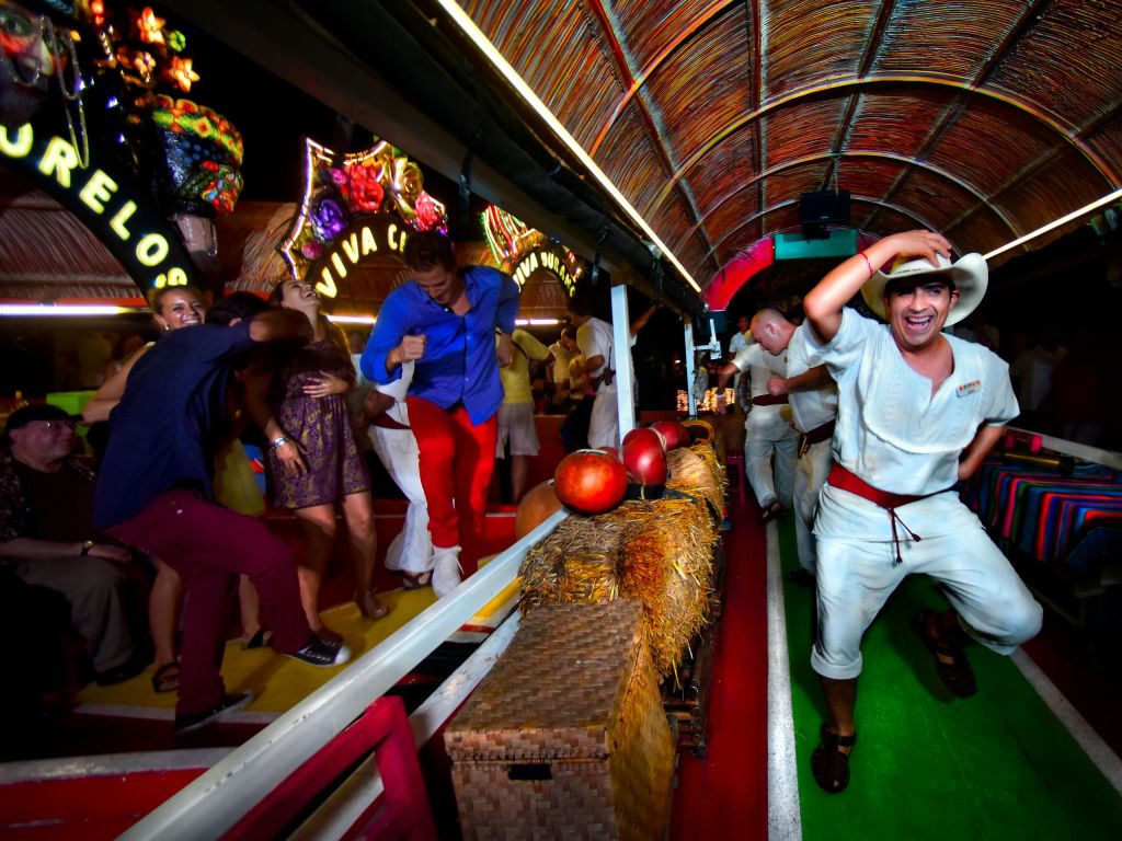 활기찬 장식과 건초가 있는 축제 보트에서 활기차게 춤을 추는 사람들은 화려한 의상과 웃는 얼굴이 특징입니다.