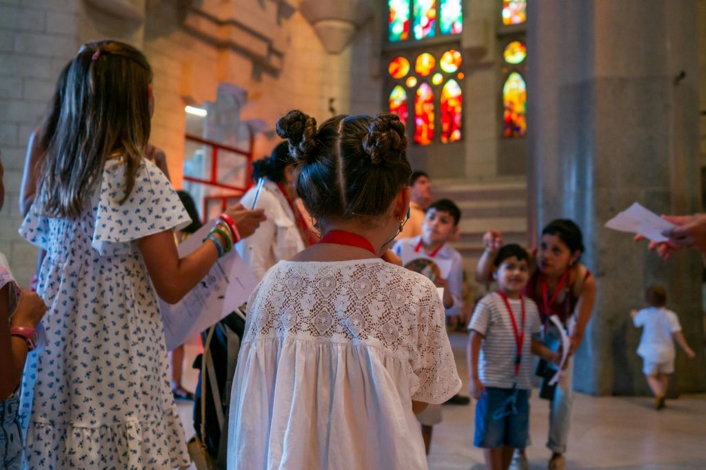 화려한 스테인드글라스 창문이 있는 건물 내부에 빨간 방아끈이 있는 어린이와 성인.