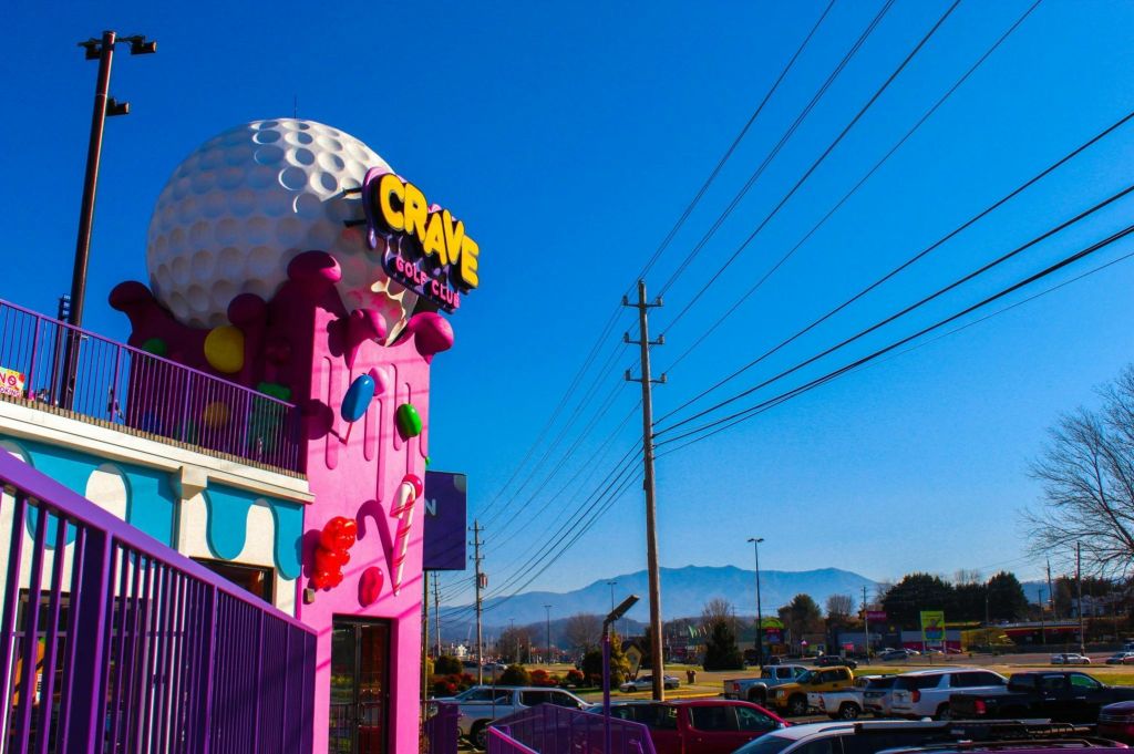 거대한 골프공 구조, 화려한 장식, 맑고 푸른 하늘 아래 주변의 동력선이 있는 크레이브 골프 클럽 건물의 외관.