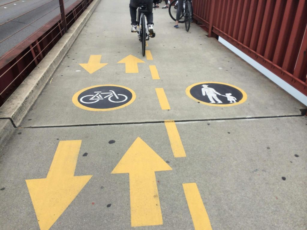 자전거와 보행자를 위한 차선을 보여주는 페인트 기호와 화살표가 있는 공용 보행자 및 자전거 도로입니다.