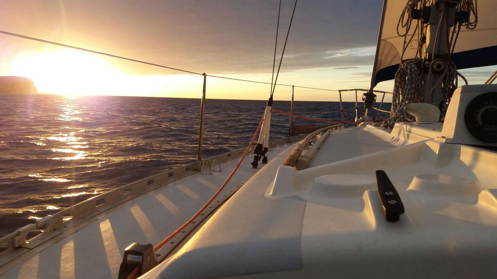 유정과 돛이 보이는 잔잔한 바다의 요트 갑판에서 바라보는 석양.
