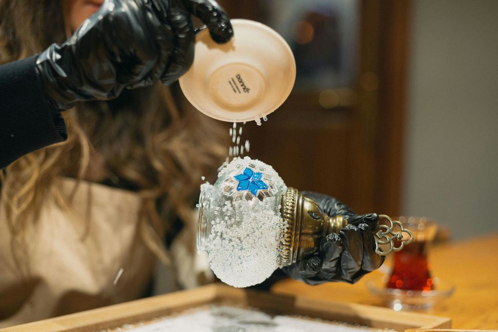 제작 중인 모자이크 램프에 작은 흰 돌을 붓는 참가자.