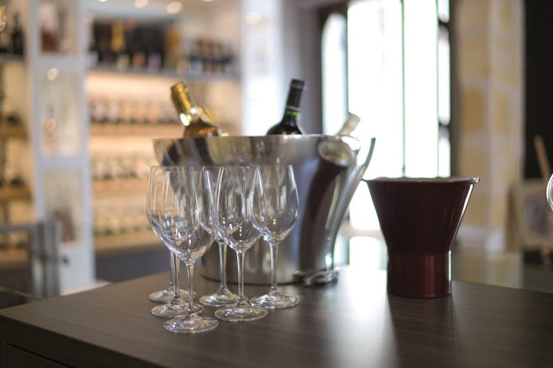 아이스 버킷에 담긴 샴페인 병, 빈 와인잔 6개, 와인 판매점의 조리대에 놓인 디켄터.