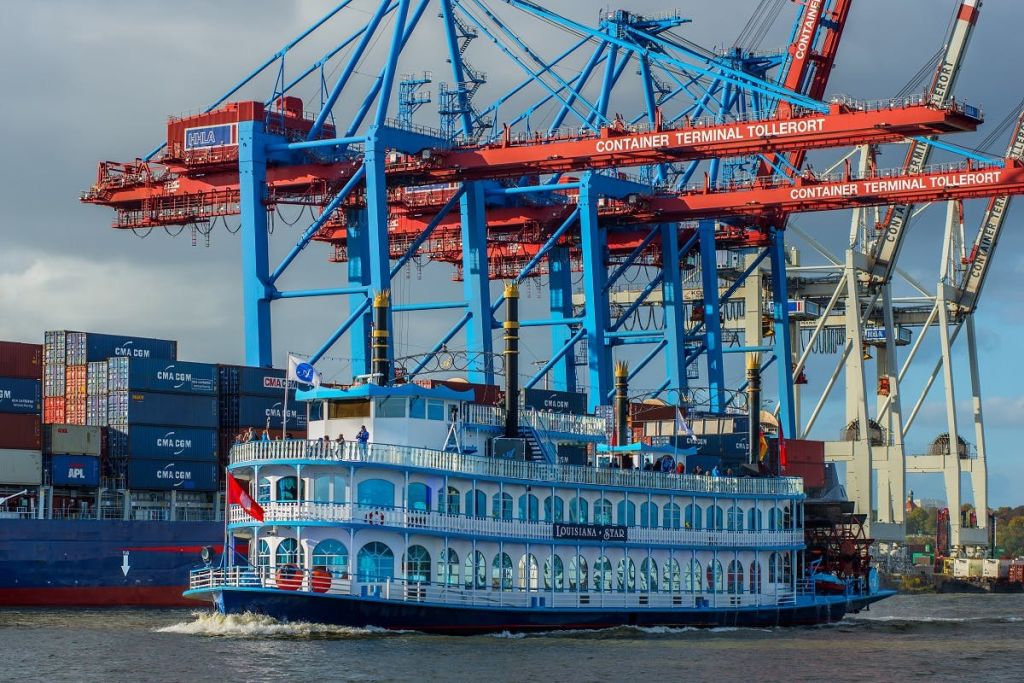 커다란 빨간색과 파란색 크레인과 선적 컨테이너를 배경으로 "루이지애나 스타" 라는 이름의 파란색 난간이 달린 패들보트.