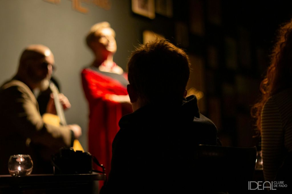 희미하게 빛나는 장면은 기타를 연주하는 뮤지션을 보는 사람과 가수가 공연하는 것을 보여줍니다. 둘 다 약간 초점이 맞지 않습니다.