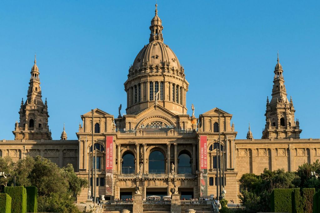 중앙 돔과 두 개의 타워가 있는 웅장한 건축 건물로 외관에 현수막이 있고 전경에 계단이 있습니다.