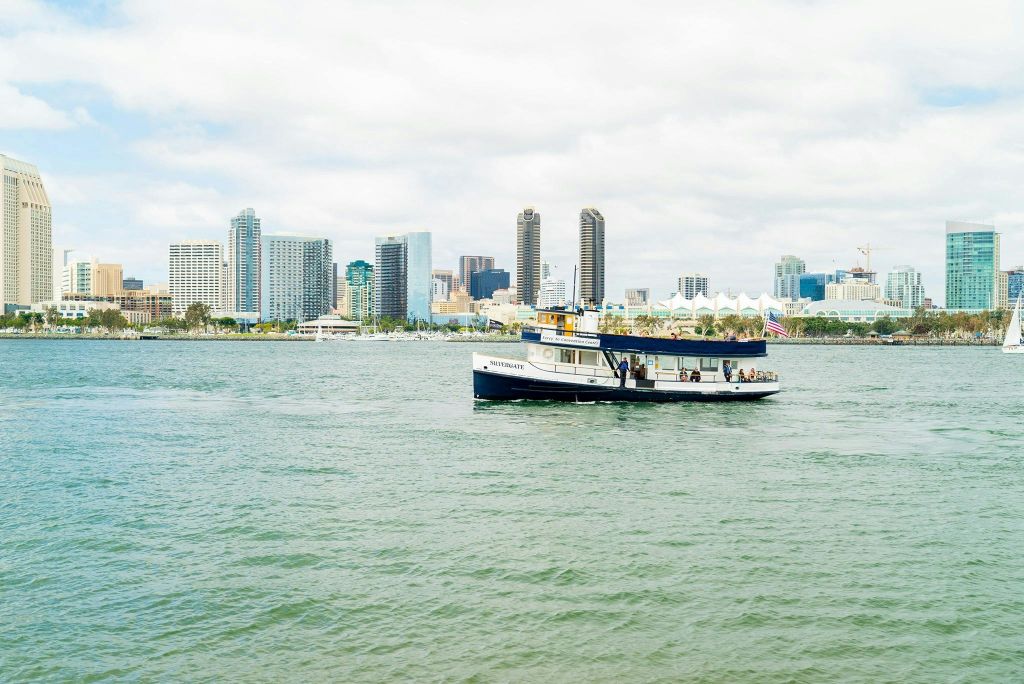 탁한 하늘 아래 높은 빌딩을 배경으로 도시의 스카이라인이 있는 전경의 작은 여객선입니다.