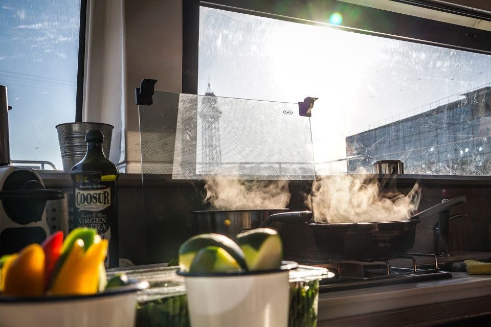 Vista de la cocina en el catamarán, con dos ollas en la estufa cocinando la cena.