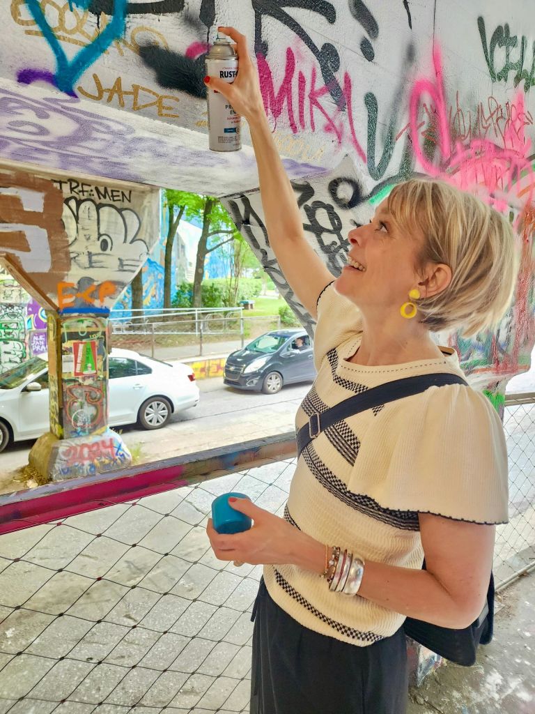 다채로운 색상의 태그와 예술품으로 덮인 벽에 그라피티를 분사해 생동감 넘치는 도시 분위기를 연출하는 사람.