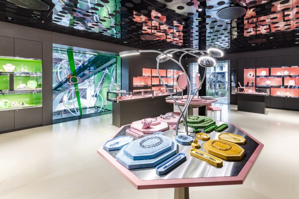 화려한 기하학적 디스플레이와 원형 조명 아래 다양한 목걸이가 있는 현대적이고 밝은 주얼리 매장.