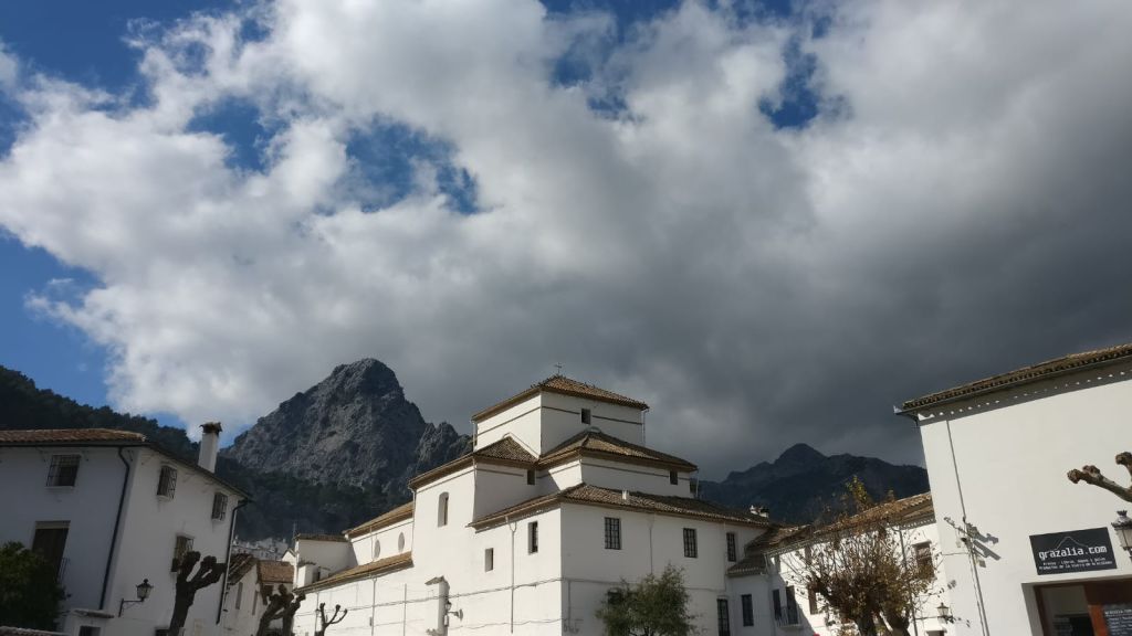 산맥을 배경으로 흐린 하늘 아래 갈색 지붕이 있는 하얀 건물.