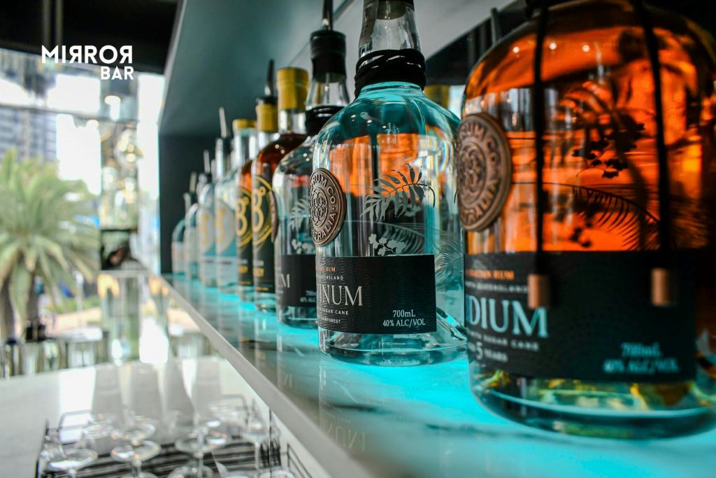 바의 조명이 밝은 선반에 표시되는 여러 프리미엄 주류 병의 클로즈업으로, 복잡한 라벨과 디자인이 특징입니다.