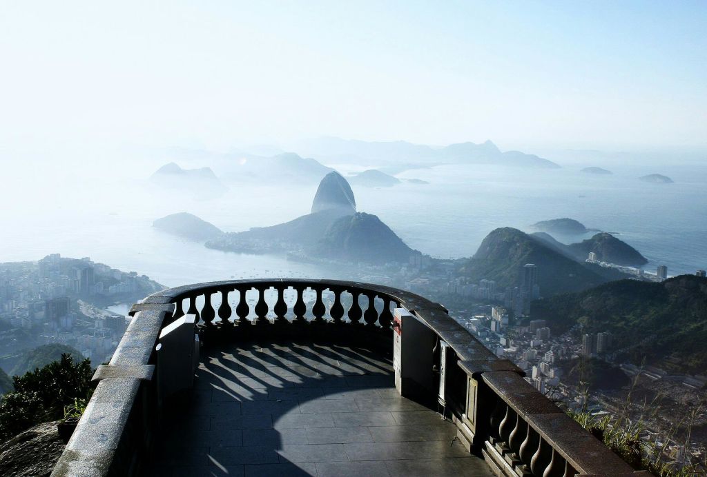 산과 물이 어우러진 도시 풍경이 내려다보이는 스톤 발코니로, 저 멀리 눈에 띄는 암석 지대가 있습니다.