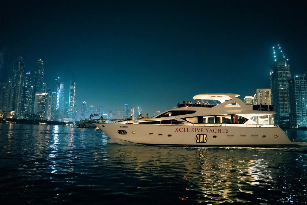 야간에 호화 요트 "프라이비트 요트" 를 타고 도시의 스카이라인을 배경으로 조명이 켜진 건물을 둘러보세요.