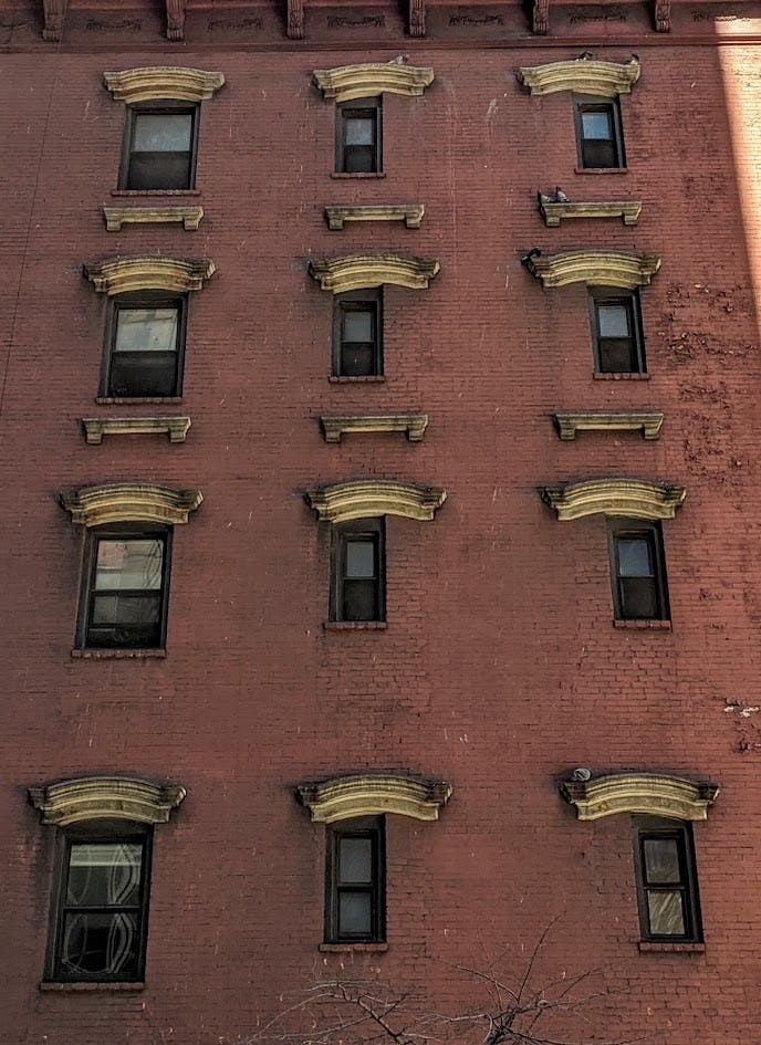 여러 개의 창문이 있는 벽돌 건물 외관으로, 각 창문 위에 장식용 돌로 포인트를 주었습니다.