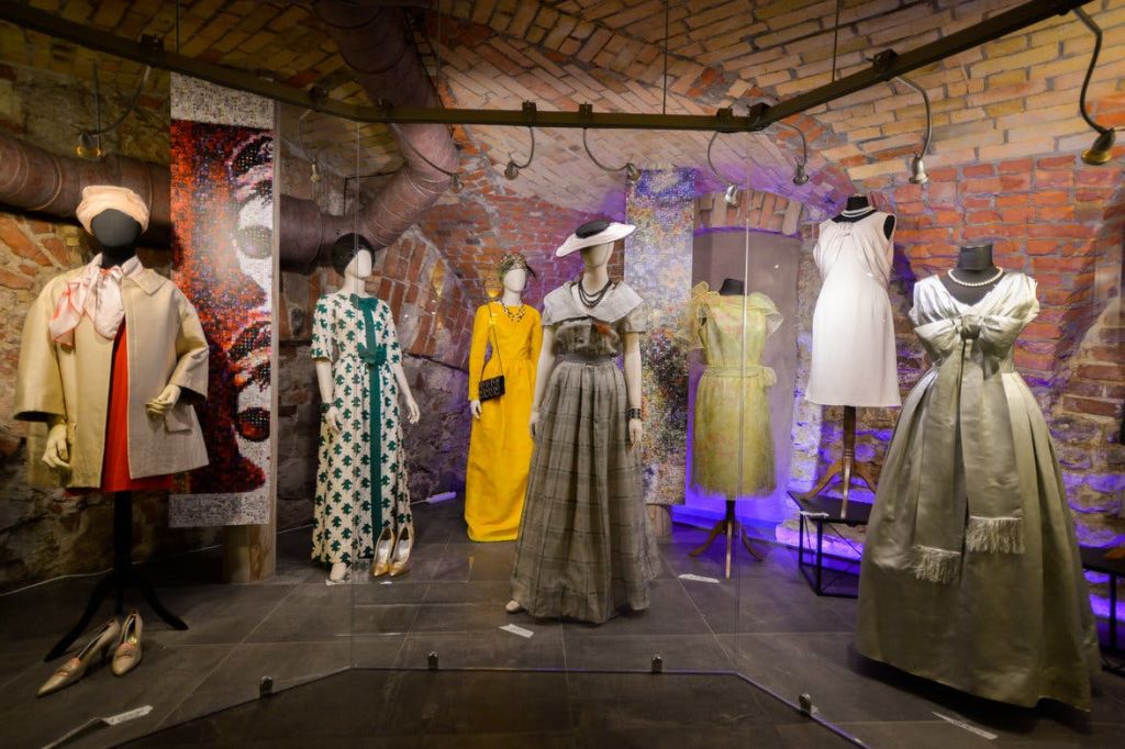 벽돌 벽으로 마감된 방의 마네킹에 빈티지 드레스가 전시되어 있으며, 의상을 강조하는 스포트라이트가 있습니다.