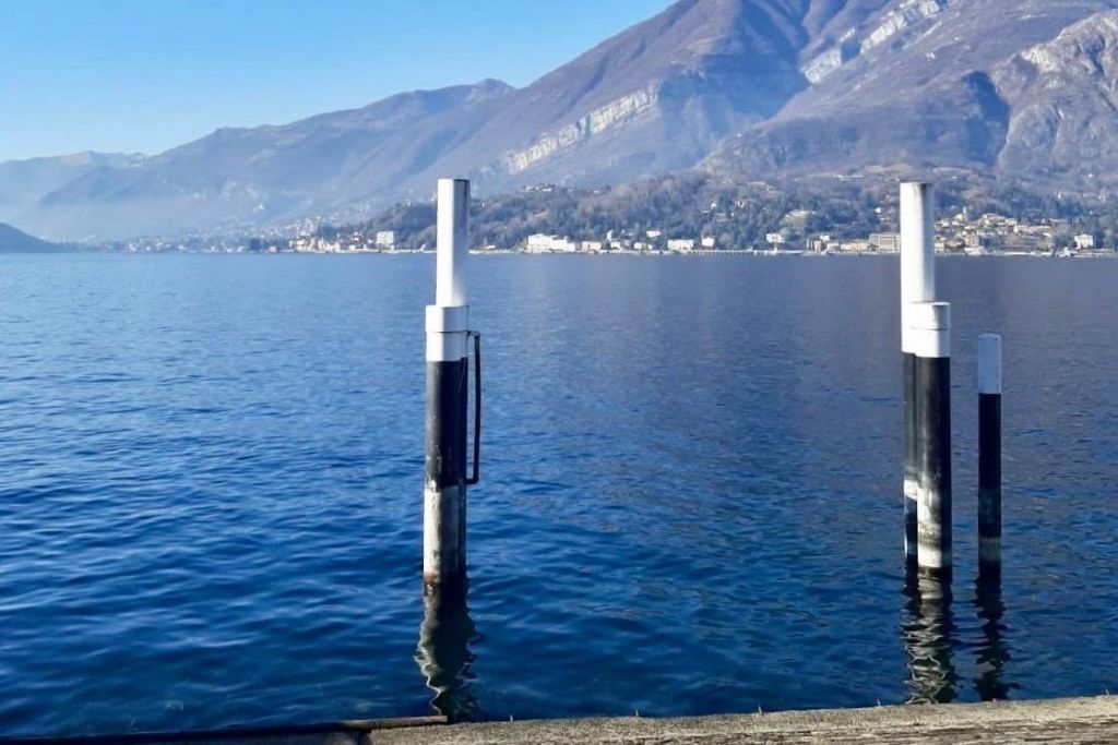 맑고 푸른 하늘 아래 마을과 산을 배경으로 잔잔한 호수에 하얀 기둥 두 개가 서 있습니다.
