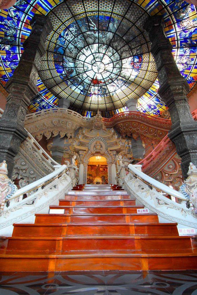 정교한 조각과 기둥이 특징인 선명한 스테인드글라스 돔으로 이어지는 웅장하고 풍성한 장식의 계단이 있는 화려한 인테리어.