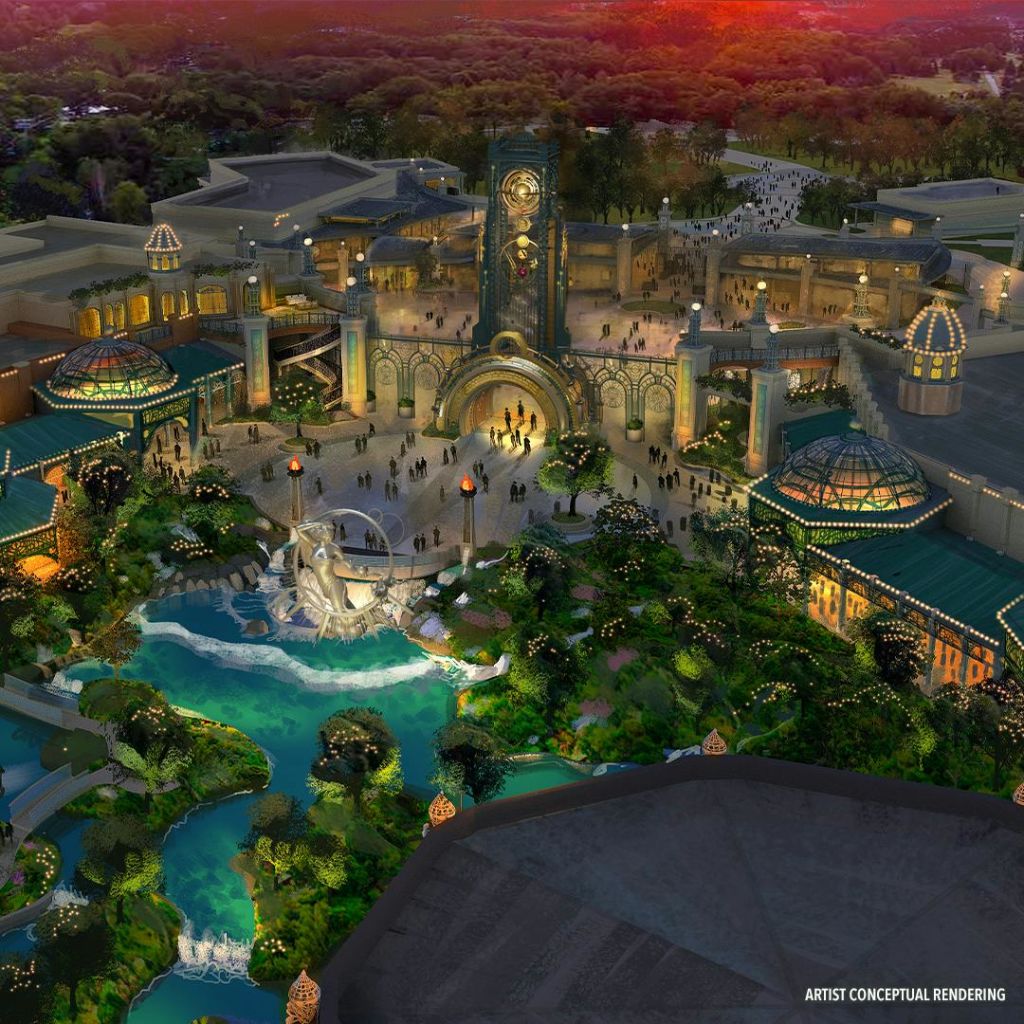 중앙 시계탑, 주변 건물, 조경된 녹지, 작은 연못이 있는 황혼의 테마파크 입구의 공중 전망.