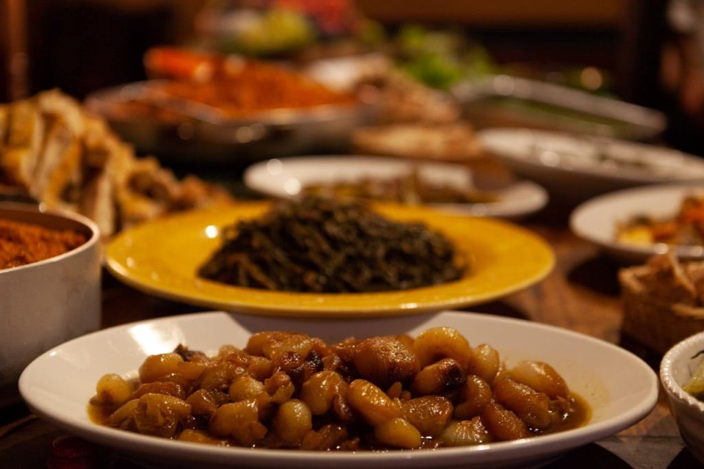 테이블 위에는 요리한 양파 한 그릇, 배경에는 채소 한 접시 등 다양한 요리가 놓여 있습니다.