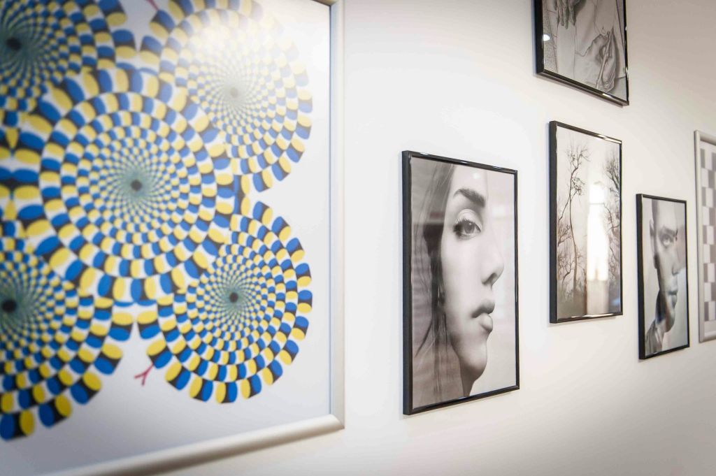 벽에 걸린 액자에 담긴 예술 작품에는 다채로운 착시 패턴, 흑백 초상화 및 기타 단색 이미지가 포함됩니다.