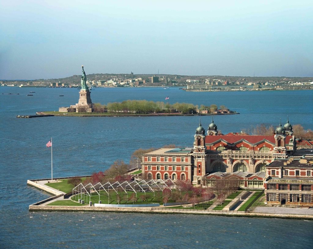 엘리스 섬 건물과 물로 둘러싸인 자유의 여신상, 도시 스카이라인을 배경으로 한 전망.