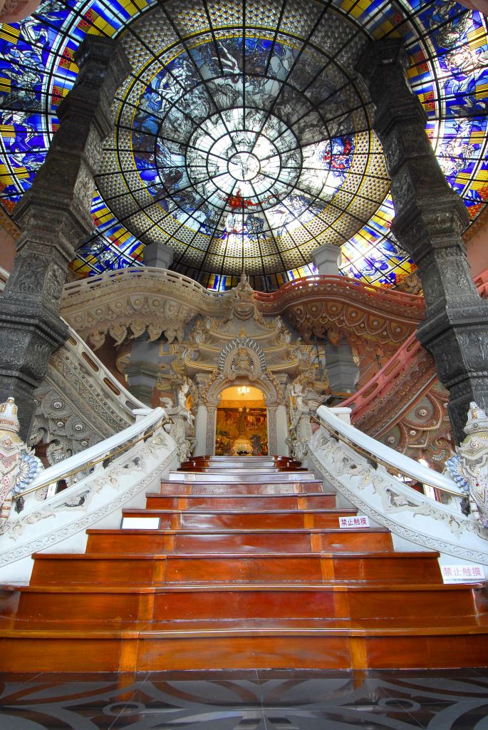 정교한 조각과 기둥이 특징인 선명한 스테인드글라스 돔으로 이어지는 웅장하고 풍성한 장식의 계단이 있는 화려한 인테리어.
