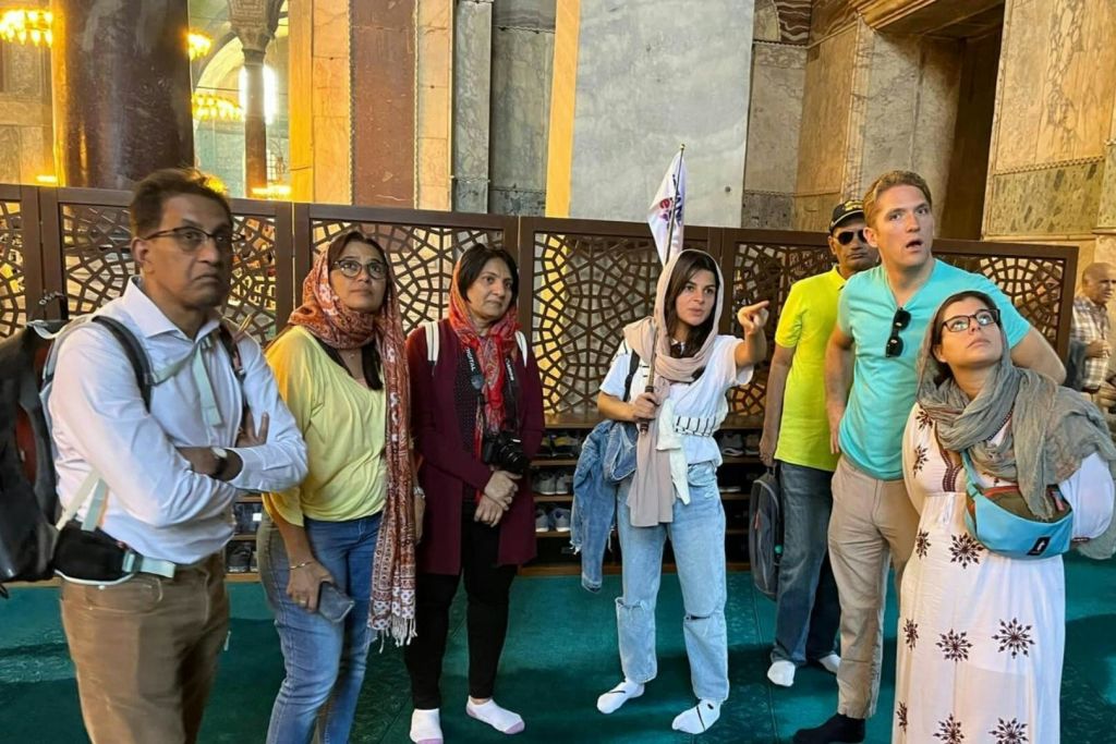 실내에 서 있는 사람들 중에는 스카프와 캐주얼한 옷을 입고 활동이나 토론에 참여하는 사람들이 있습니다.