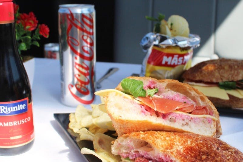 코카콜라 캔과 칩 봉지를 배경으로 한 접시에 칩을 곁들인 샌드위치가 제공됩니다.