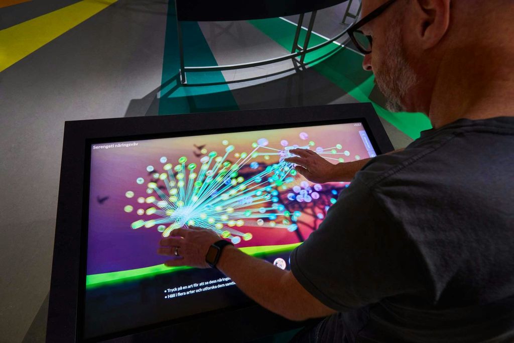 한 사람이 다채로운 네트워크 다이어그램을 표시하는 터치스크린 테이블과 상호 작용합니다.