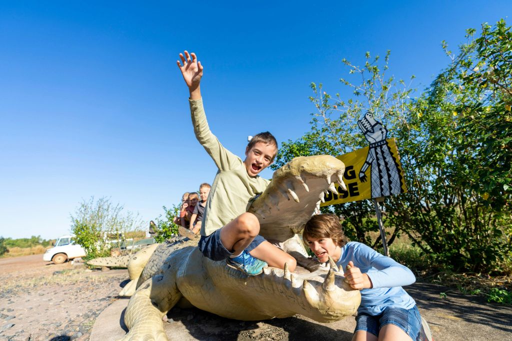 커다란 악어 조각상과 함께 포즈를 취하는 어린이들