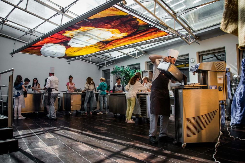 셰프가 도와주는 현대적인 주방에서 요리하는 사람들로, 다채로운 색상의 커다란 천장 벽화 아래 있습니다.