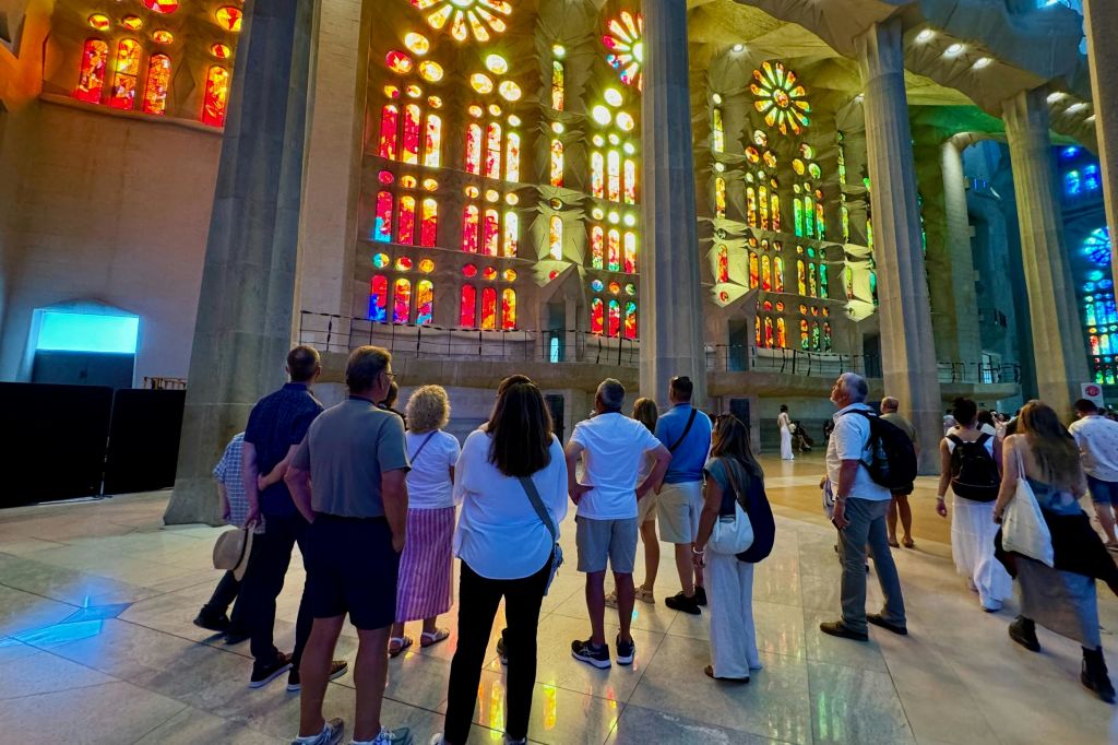 내부에서 사그라다 파밀리아 (Sagrada Familia) 의 화려한 스테인드글라스 창문을 관찰하는 방문객들.