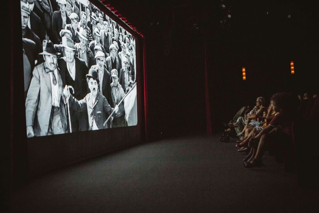 어두운 극장에서 흑백 영화 찰리 채플린을 보는 사람들. 청중은 오른쪽에 앉습니다.