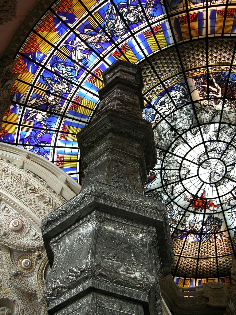 생동감 넘치는 스테인드글라스 창문과 정교한 조각이 돋보이는 화려한 천장, 정교한 구조가 돋보이는 중앙 기둥 프레임.