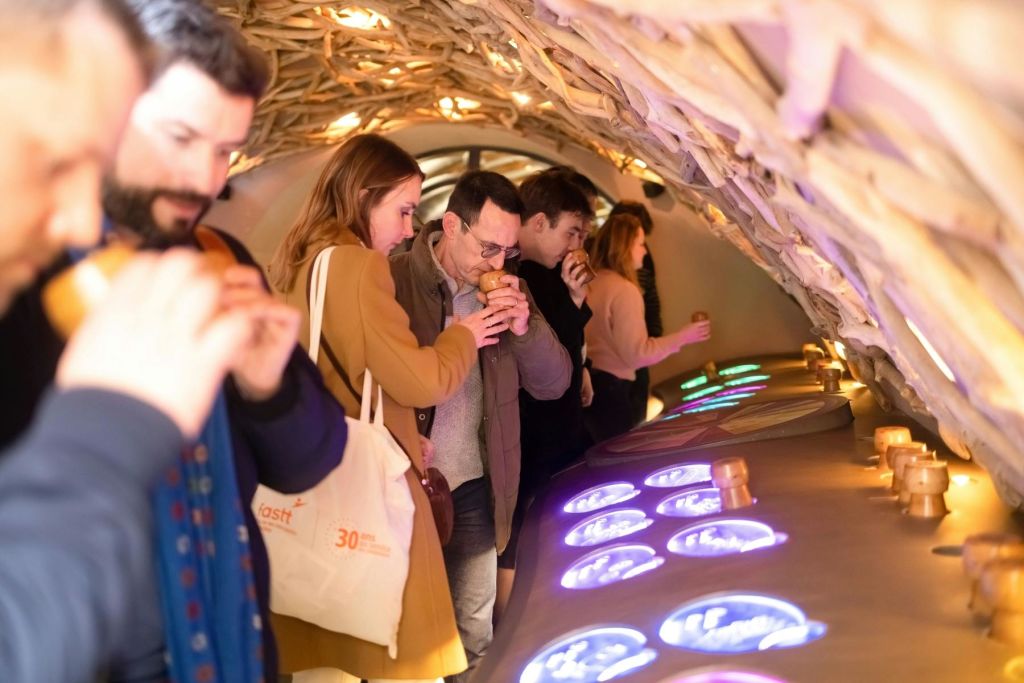 사람들은 나무 아치 아래에 줄을 서서 물건을 코에 붙이고 감각 활동을 할 수 있습니다.