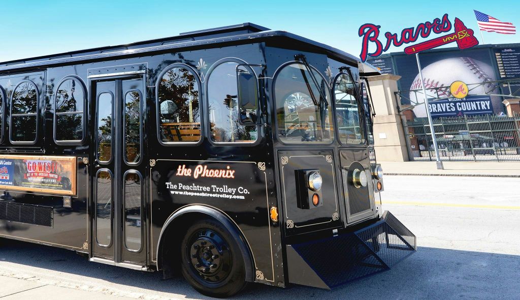 부분적으로 보이는 "Braves" 표지판이 있는 건물을 배경으로 "The Phoenix, The Peachtree Trolley Co." 라고 표시된 검은색 트롤리.