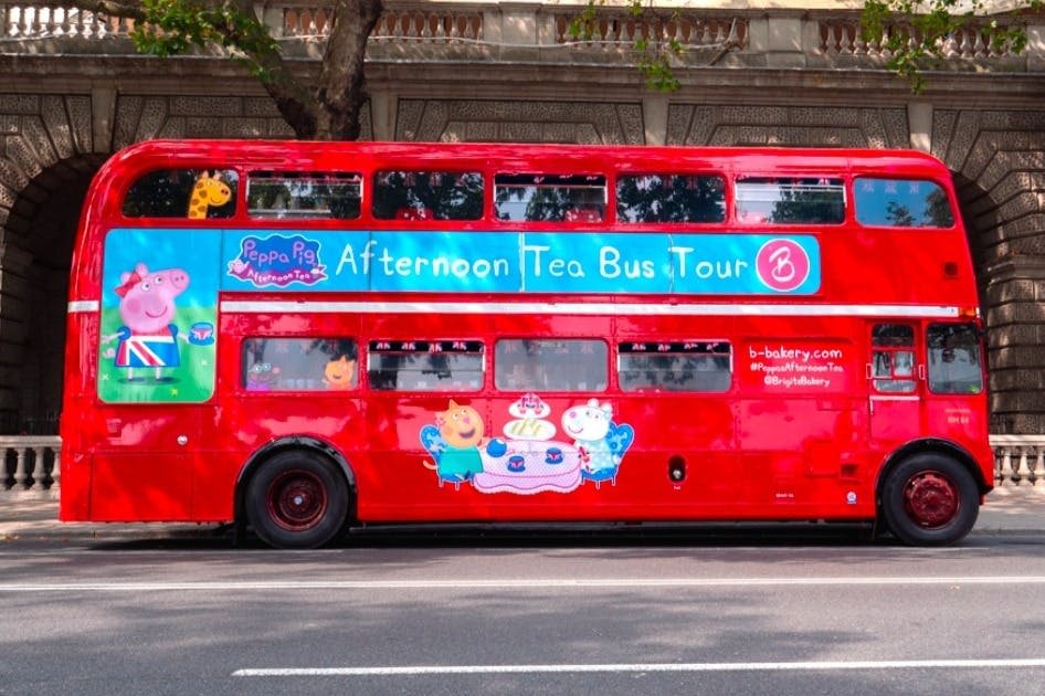 애프터눈 티 버스 투어를 위한 페파 피그 테마 장식이 있는 빨간색 2층 버스가 거리에 주차되어 있습니다.