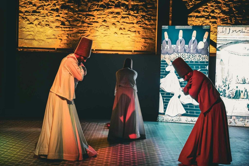 장식적인 배경과 따뜻한 조명이 있는 무대에서 춤을 추는 전통 복장의 세 가지 소용돌이 장식.