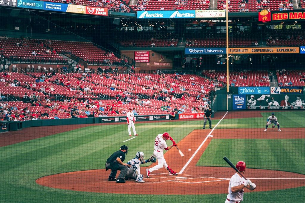 타자가 공을 치고 관중이 스탠드에 앉아 경기장에서 진행 중인 야구 경기.