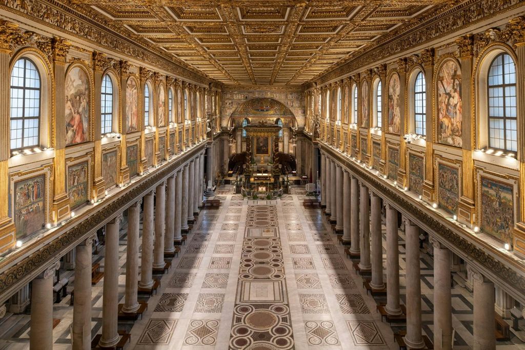 대리석 기둥, 아치형 창문, 정교한 천장, 웅장한 제단이 있는 넓고 화려하게 장식된 교회 내부.