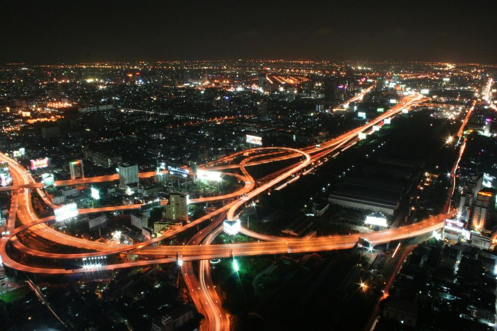 밤에는 건물과 가로등으로 둘러싸인 조명 고속도로와 고가도로가 있는 도시의 공중 전망을 감상할 수 있습니다.