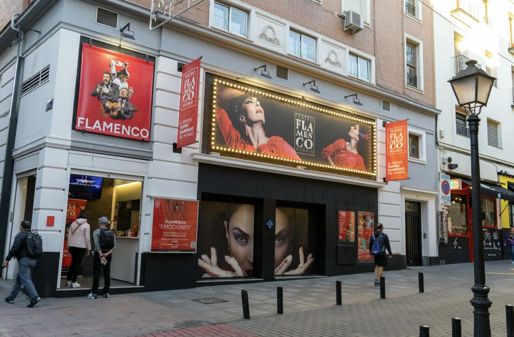 플라멩코를 테마로 한 포스터가 놓인 극장 입구와 공연 광고를 표시하는 불빛이 들어오는 마키가 있습니다.