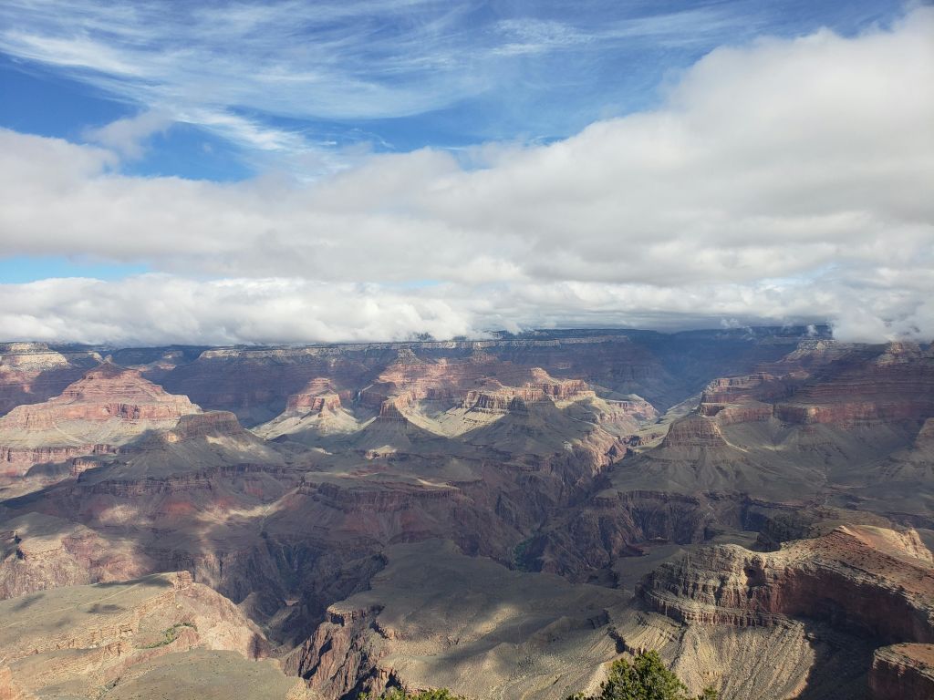 구름은 부분적으로 흐린 하늘 아래에서 층층이 쌓인 암석을 선보이며 그랜드캐니언의 전경을 감상할 수 있습니다.