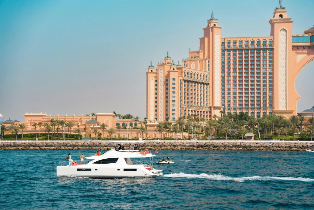 하얀 요트와 제트스키가 있는 호화 리조트로, 물가 옆에는 야자수가 있습니다.