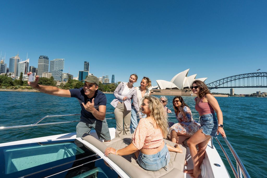 시드니 하버 보트 투어를 즐기는 그룹. 아이콘을 배경으로 사진 찍기