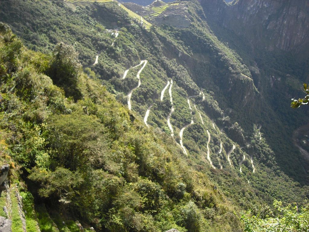 구불구불한 지그재그 도로가 산악 지형의 가파르고 울창한 산악 지대를 오릅니다.
