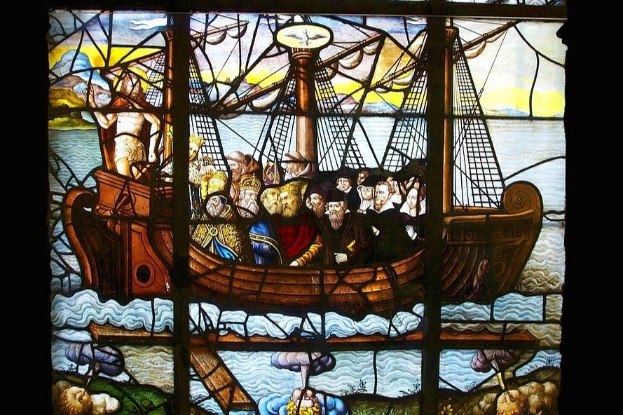 바다의 파도와 흐린 하늘을 배경으로 나무 배를 타고 역사적인 복장을 한 사람들의 스테인드글라스 작품.