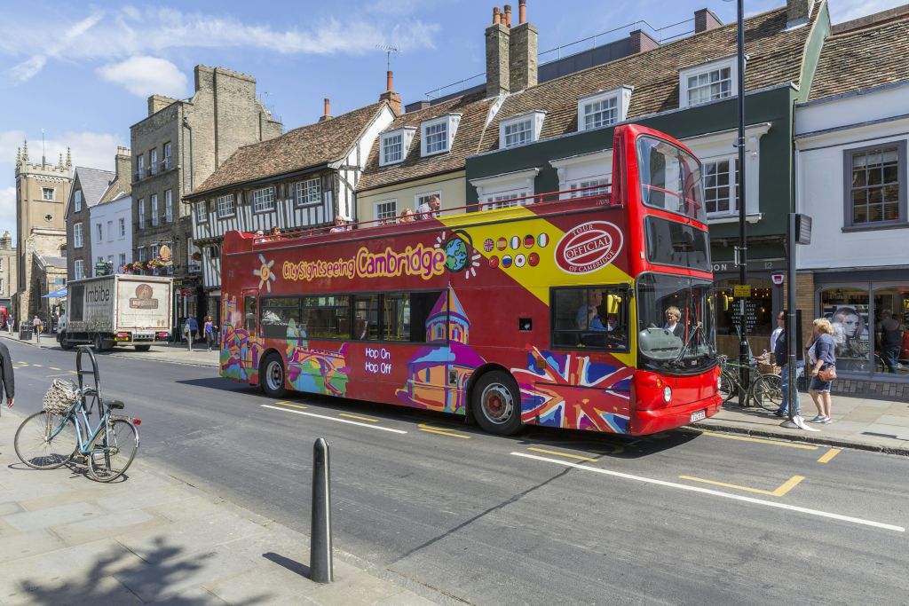 오래된 건물이 늘어선 거리에 '케임브리지 시내 관광' 이라는 이름의 다채로운 2층 관광 버스가 있습니다.